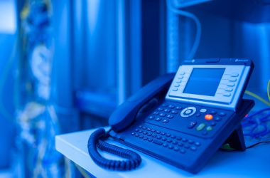 Close-up of a modern office phone in blue lighting. Ideal for tech and business themes.